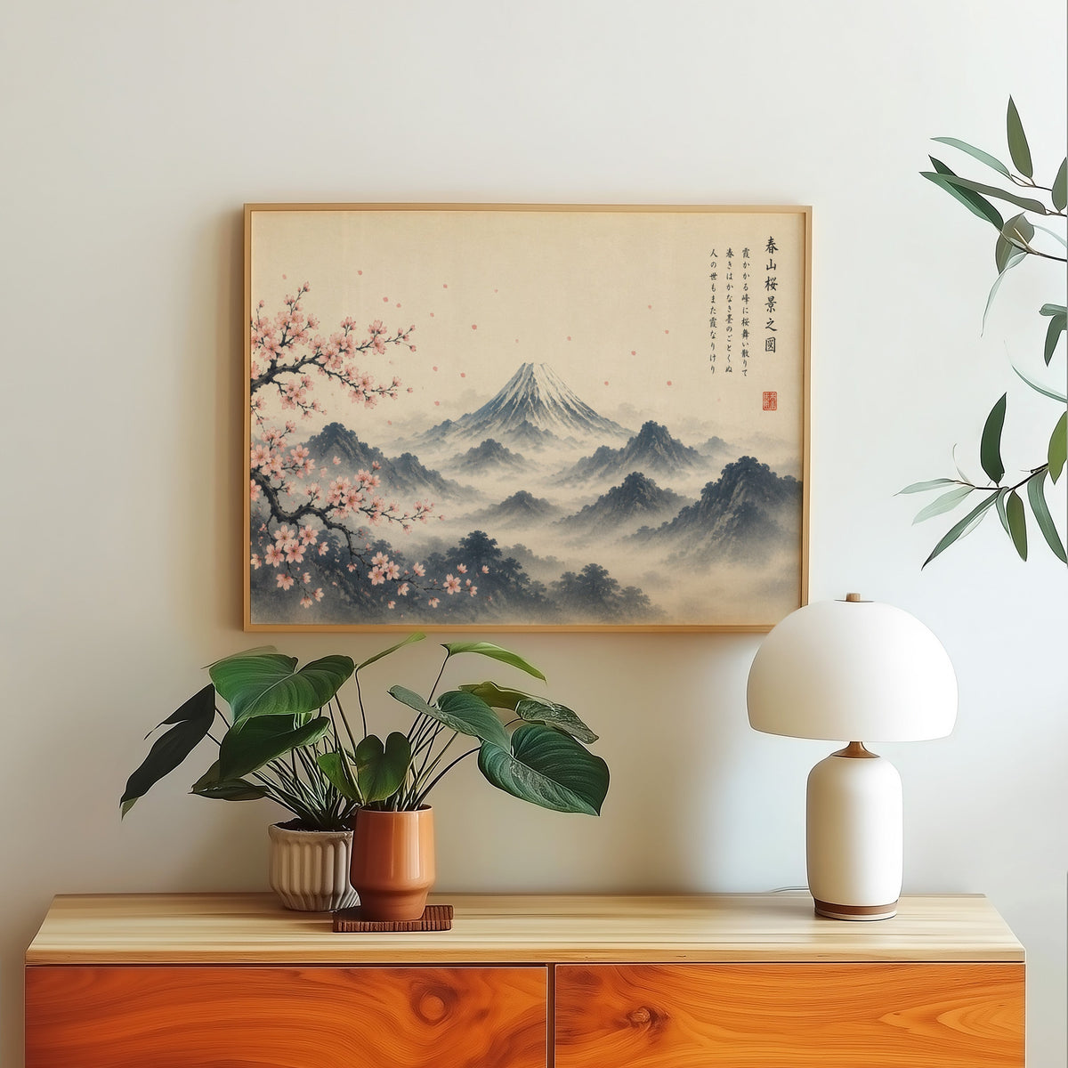 Mount Fuji and sakura ink painting print in a light oak frame above a wood sideboard with a white dome lamp