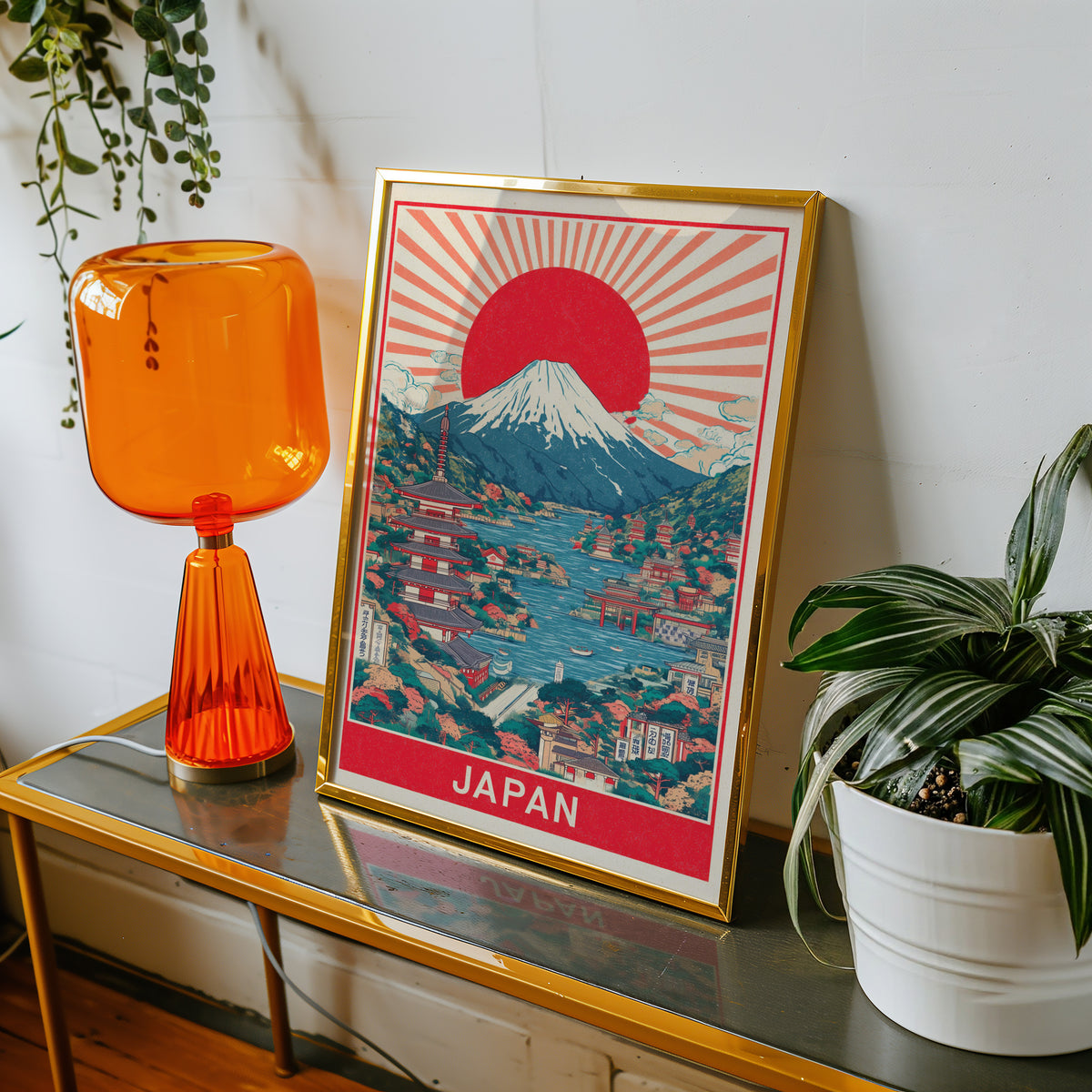 Mount Fuji sunburst lake print shown in a gold frame on a console beside an orange glass lamp