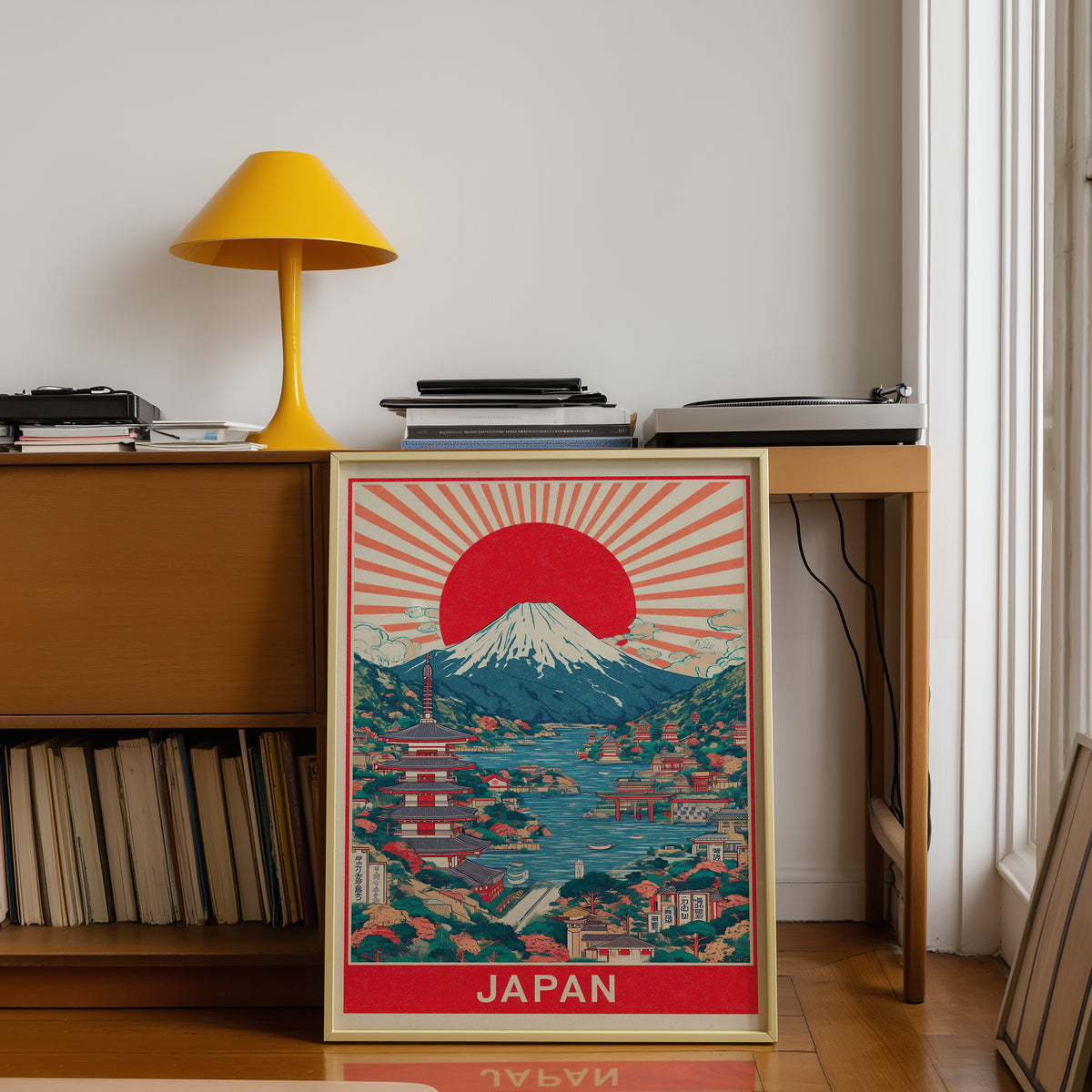 Mount Fuji sunburst lake print shown in a gold frame below a teak desk with a yellow lamp