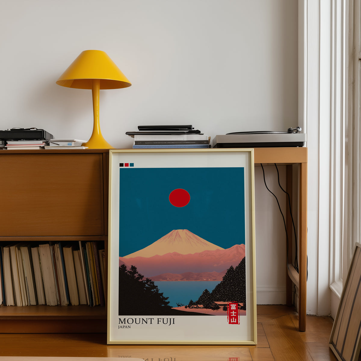 Minimalist Fuji teal sky print shown in a gold frame below a teak desk with a yellow lamp