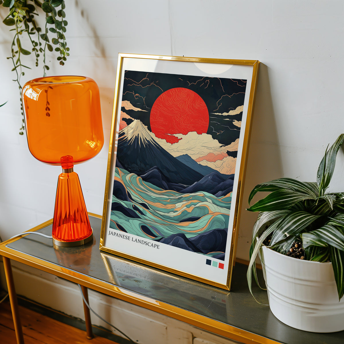 Fuji teal waves red sun print shown in a gold frame on a console beside an orange glass lamp