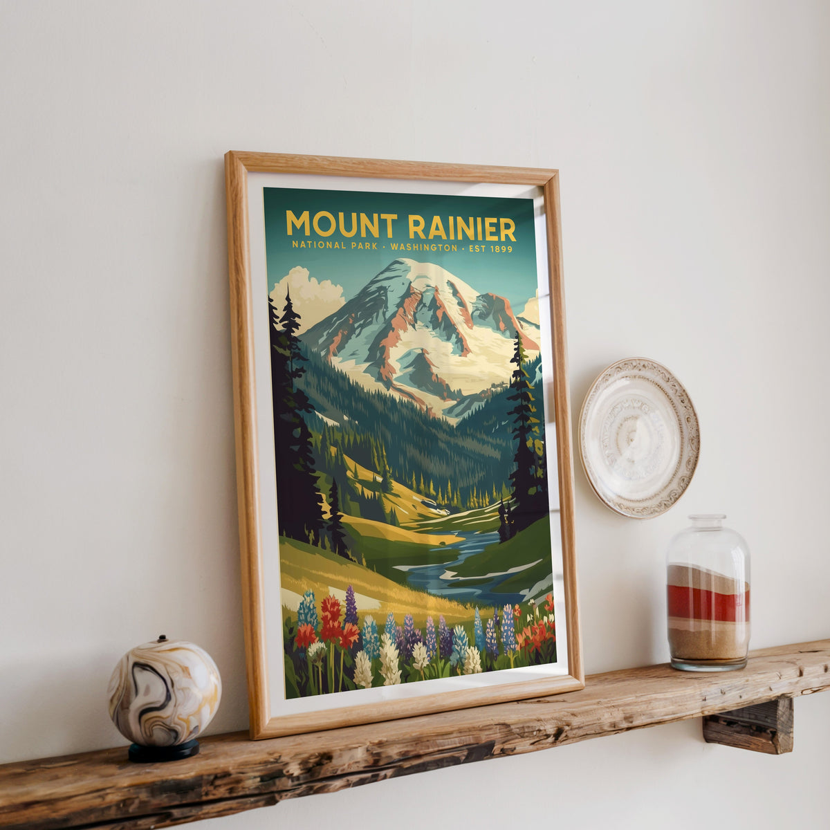 Mount Rainier National Park print in an oak frame on a wood shelf with ceramics and a sand-filled jar