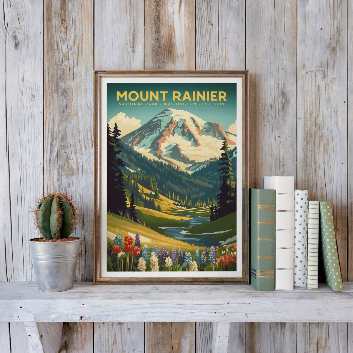 Mount Rainier poster in an antique gold frame against whitewashed planks beside books and a cactus
