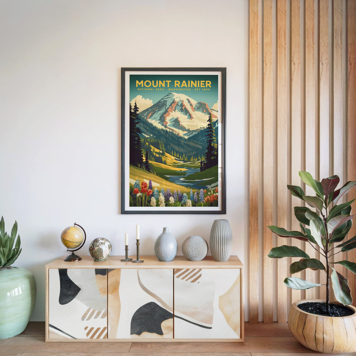 Mount Rainier National Park print in a black frame above a light wood sideboard with a globe and ceramic vases