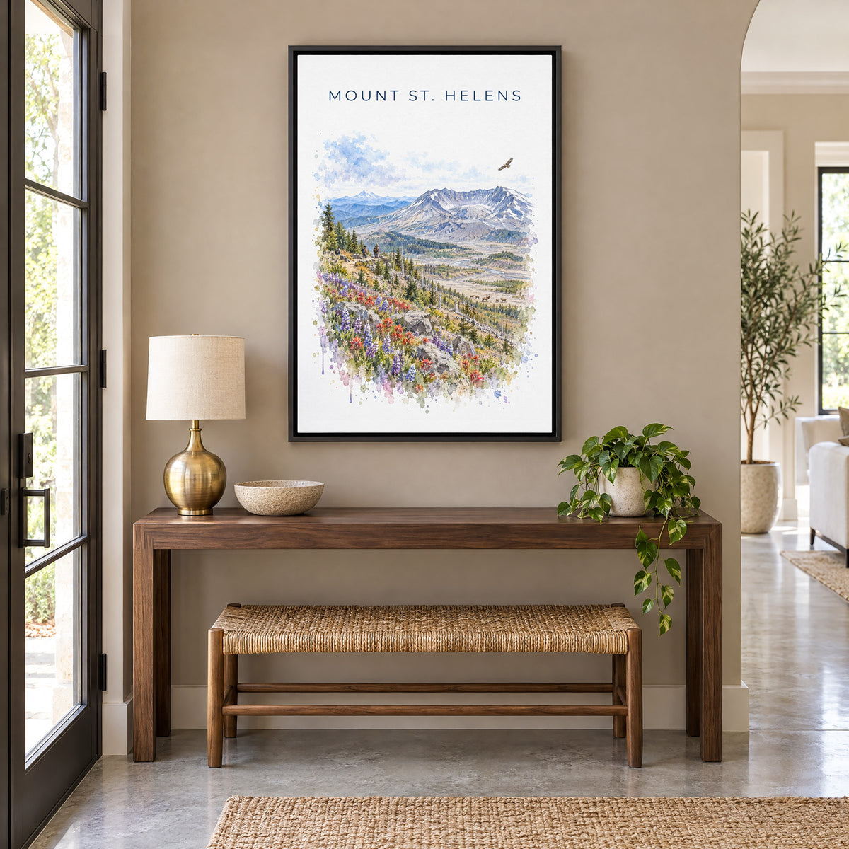 Mount St. Helens watercolor print as a black floater canvas above a walnut console and woven bench in an entryway