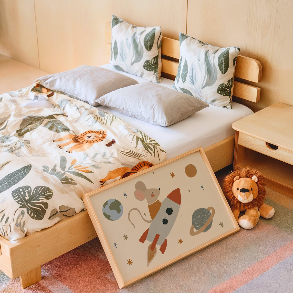 Landscape mouse astronaut riding rocket nursery print in an oak frame leaning on a kids bed by a lion plush