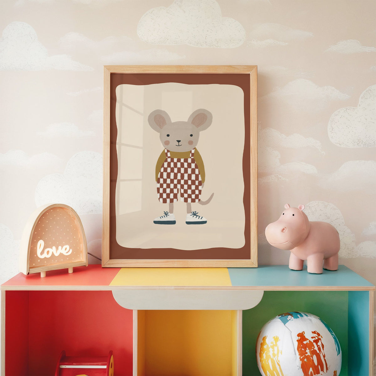 Mouse checkered overalls nursery print in an oak frame on a rainbow toy shelf against cloud wallpaper