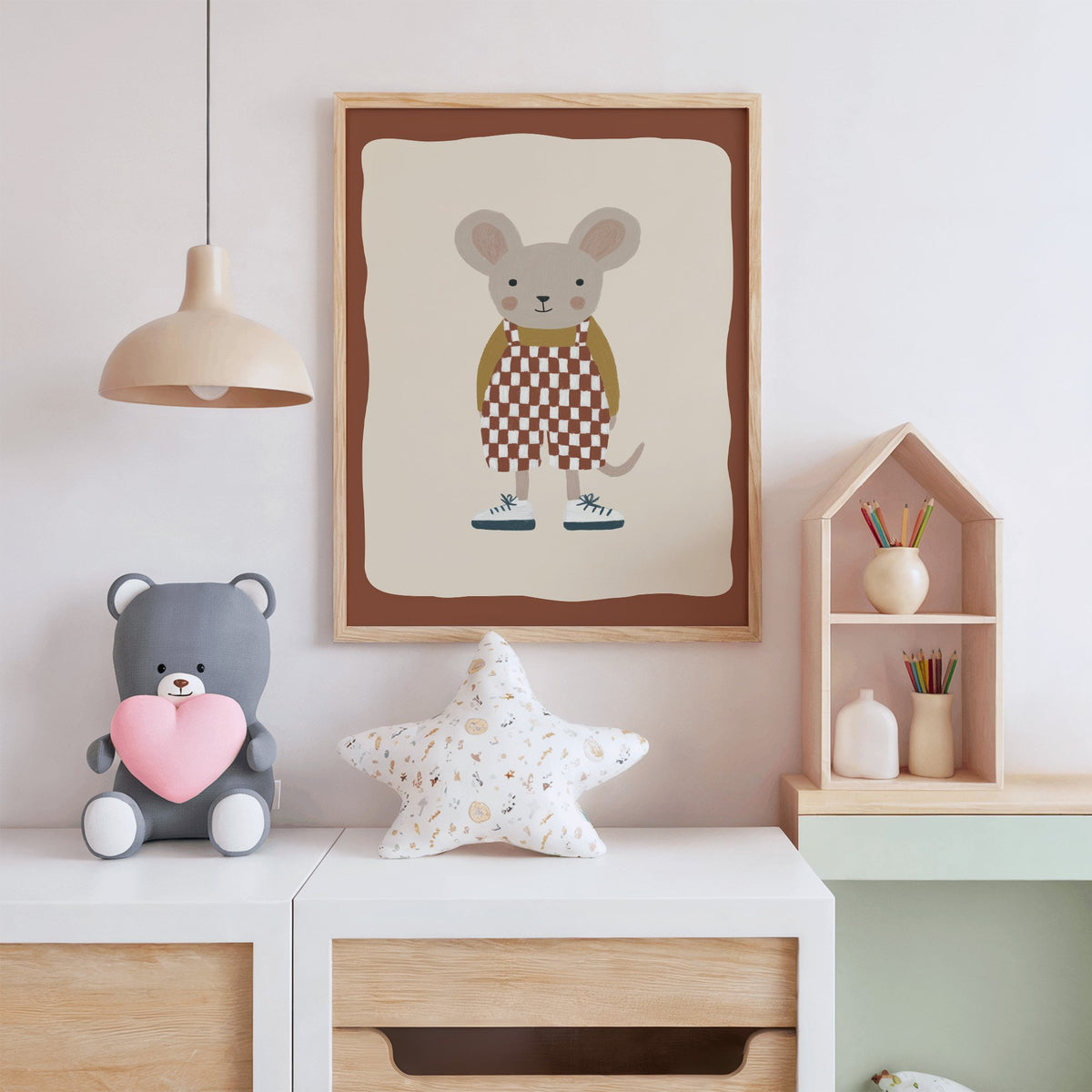 Mouse checkered overalls nursery print in an oak frame above a white dresser with a star pillow and house shelf