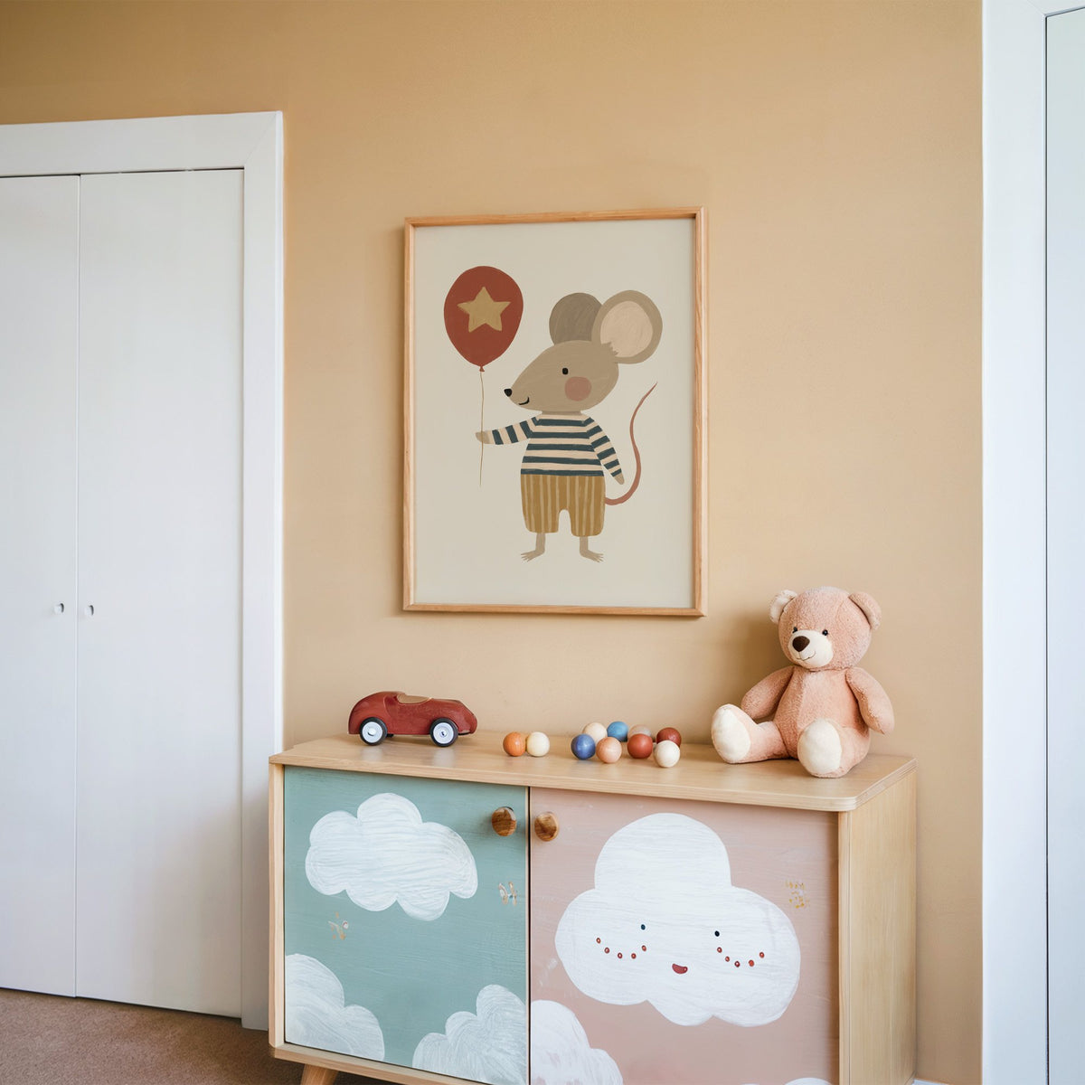 Mouse star balloon striped shirt nursery print in an oak frame on a peach wall above a cloud-painted cabinet