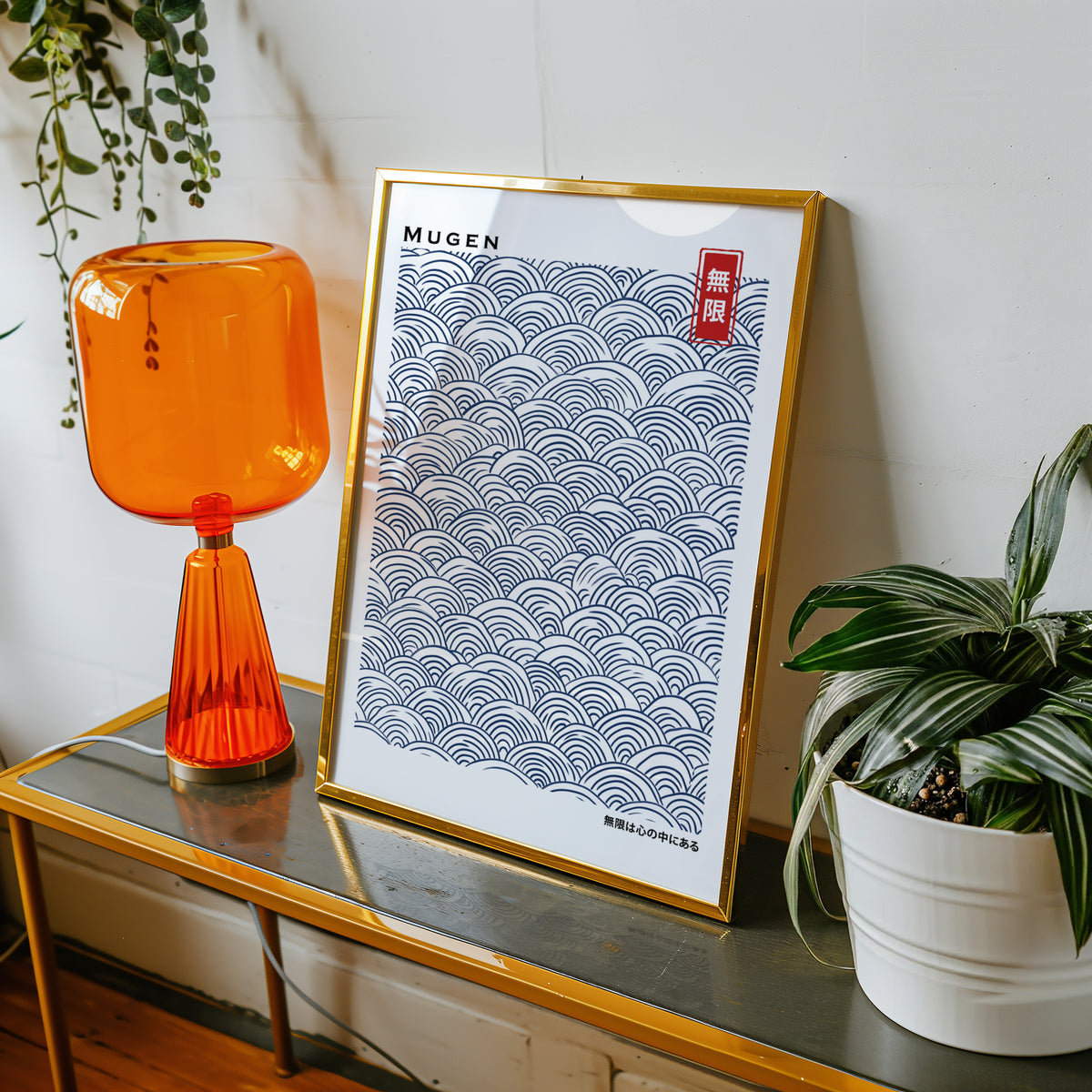 Navy seigaiha wave pattern print shown in a gold frame on a console beside an orange glass lamp