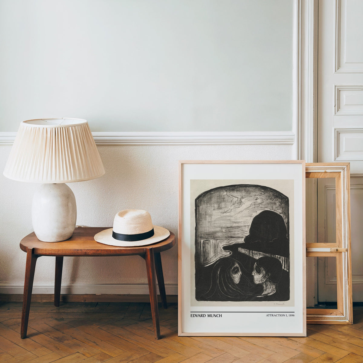 Munch poster in a light wood frame leaning by a bench and panama hat