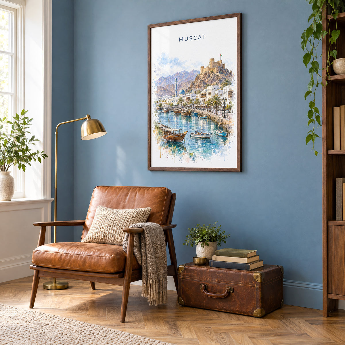Muscat watercolor print in a walnut frame on a blue wall above a leather armchair in a reading nook
