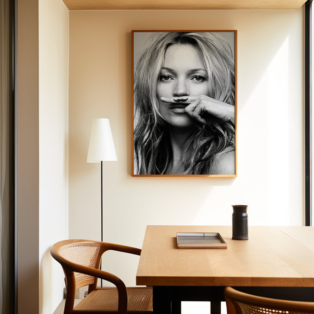 Close portrait with finger mustache under nose print in an oak frame above a dining table and cane chair