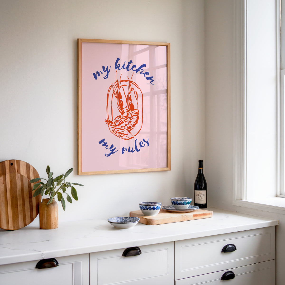 My Kitchen My Rules shrimp print in an oak frame above a white kitchen sideboard
