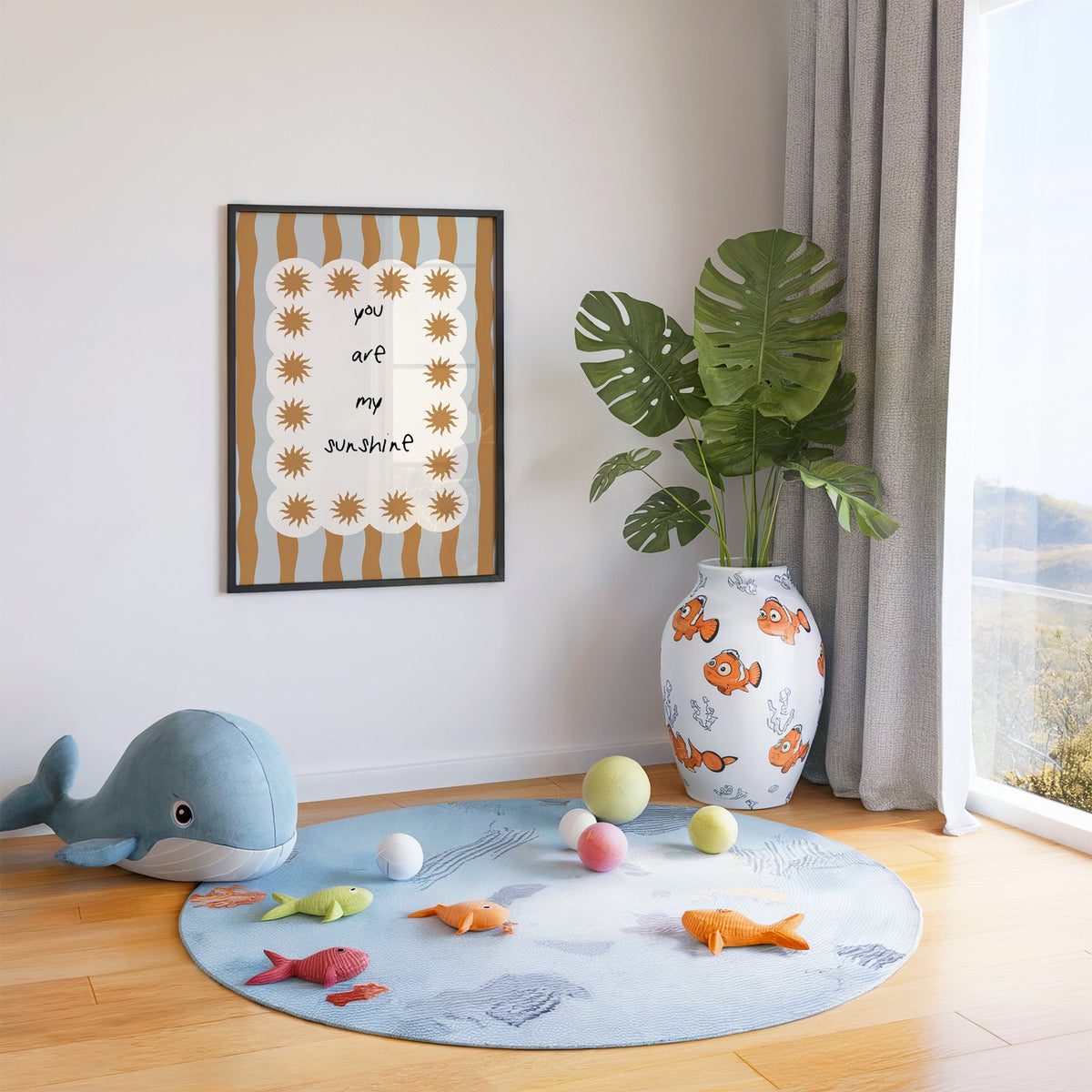 My sunshine sun border nursery print in a black frame in a playroom with an ocean rug and whale plush