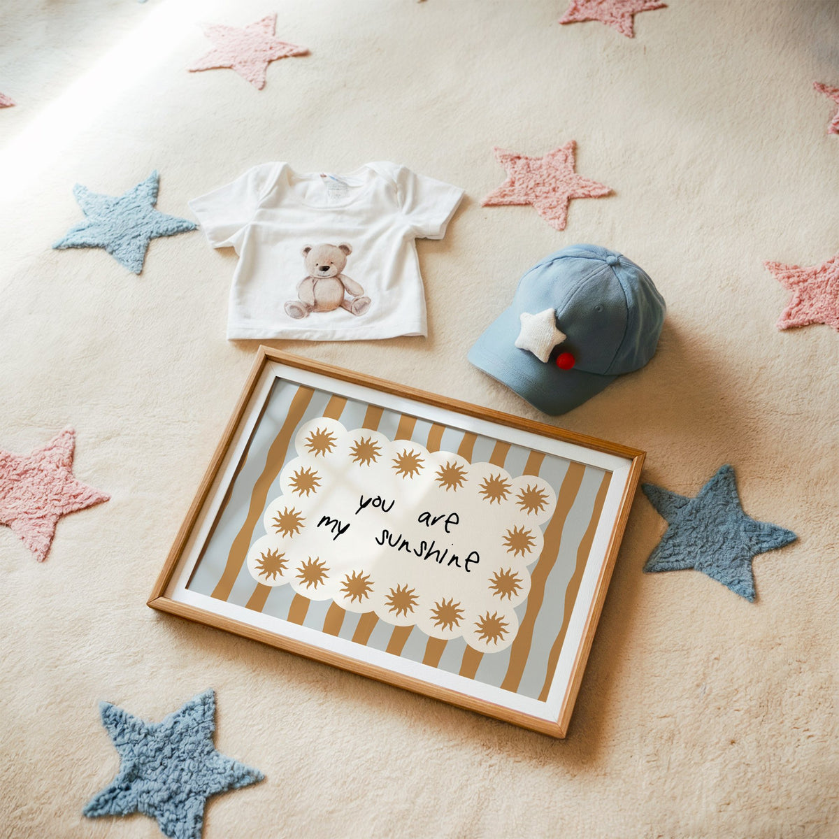 Landscape my sunshine sun border nursery print in a matted oak frame on a star rug with a baby tee