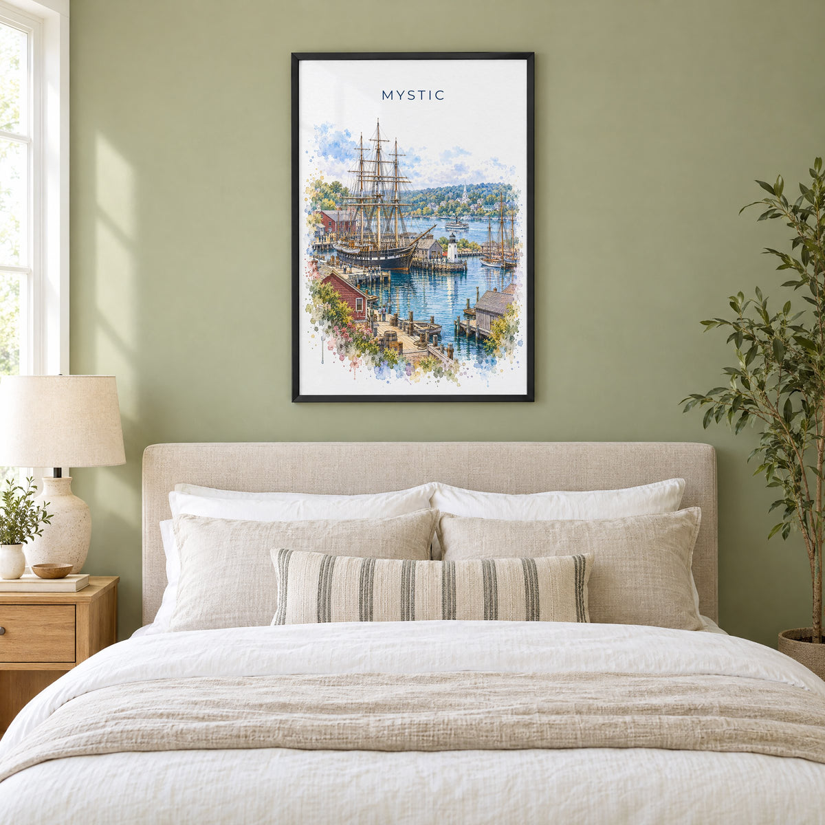 Mystic, Connecticut watercolor print in a black frame above an upholstered headboard in a sage green bedroom