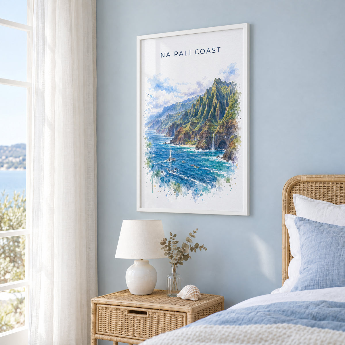 Na Pali Coast watercolor print in a white frame on a pale blue wall beside a rattan bed in a coastal bedroom