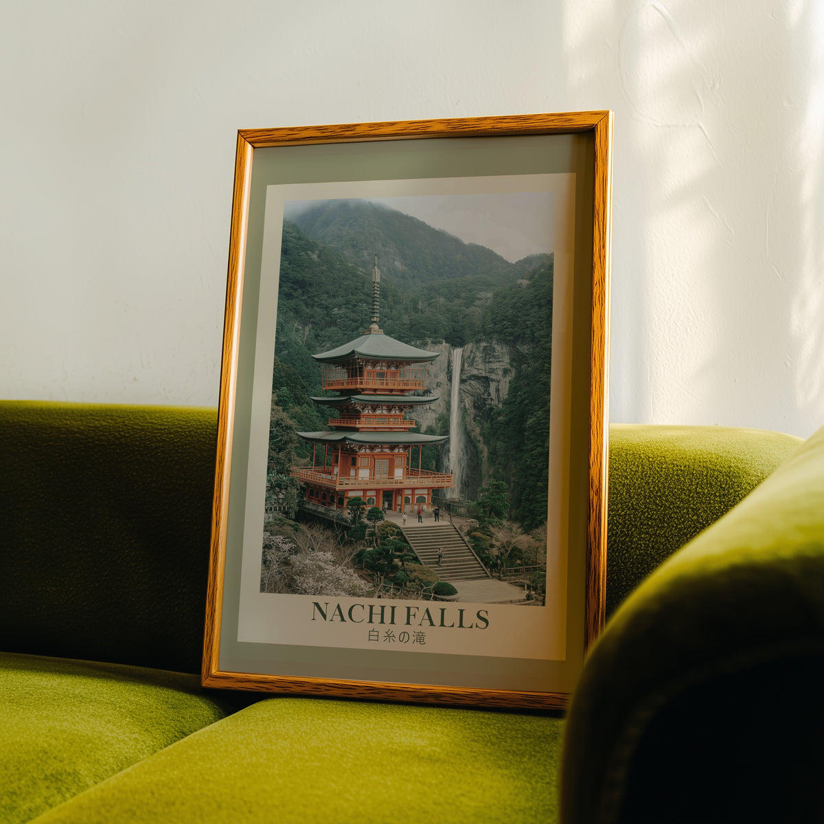 Nachi Falls and red pagoda print in an oak frame propped on a green velvet sofa