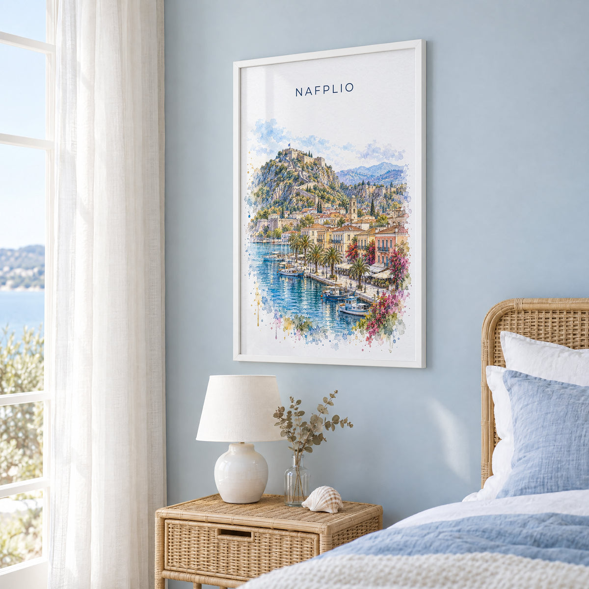 Nafplio watercolor print in a white frame on a pale blue wall beside a rattan bed in a coastal bedroom