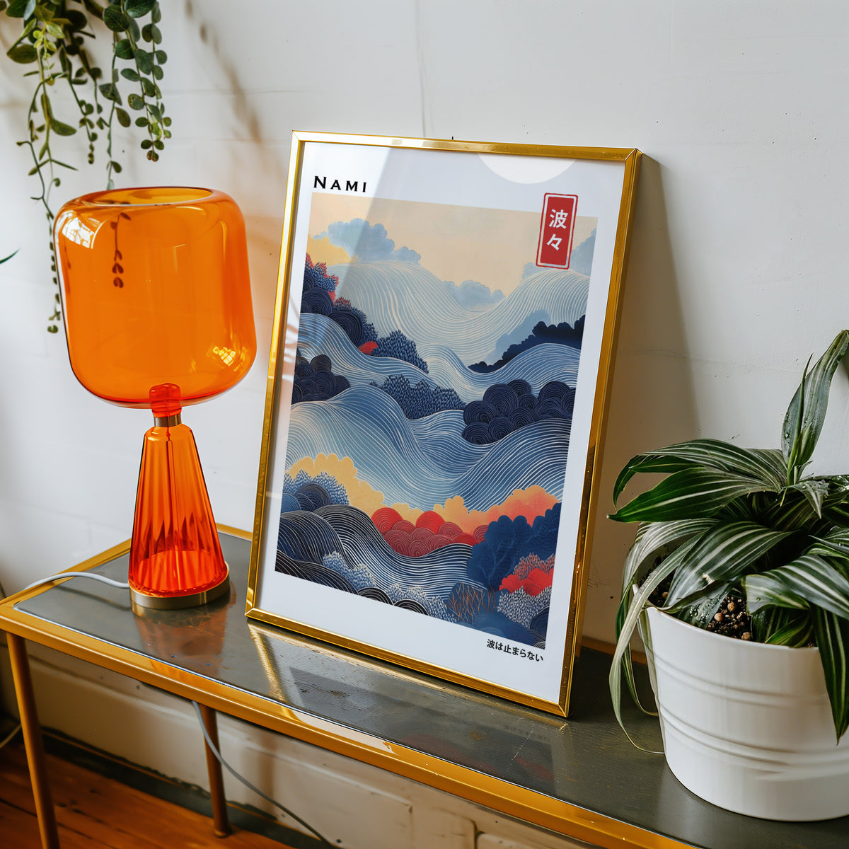 Blue layered Nami wave print shown in a gold frame on a console beside an orange glass lamp
