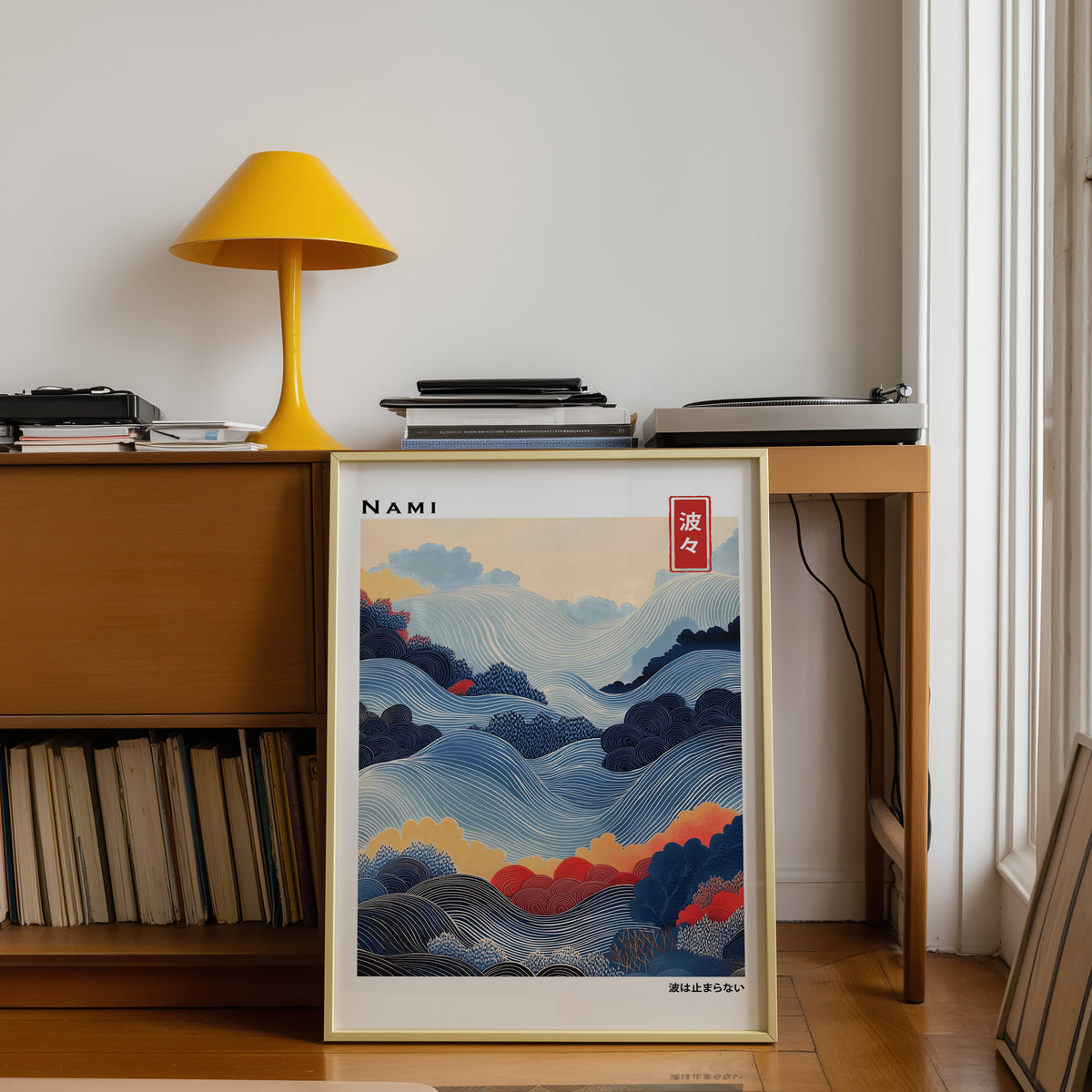 Blue layered Nami wave print shown in a gold frame below a teak desk with a yellow lamp