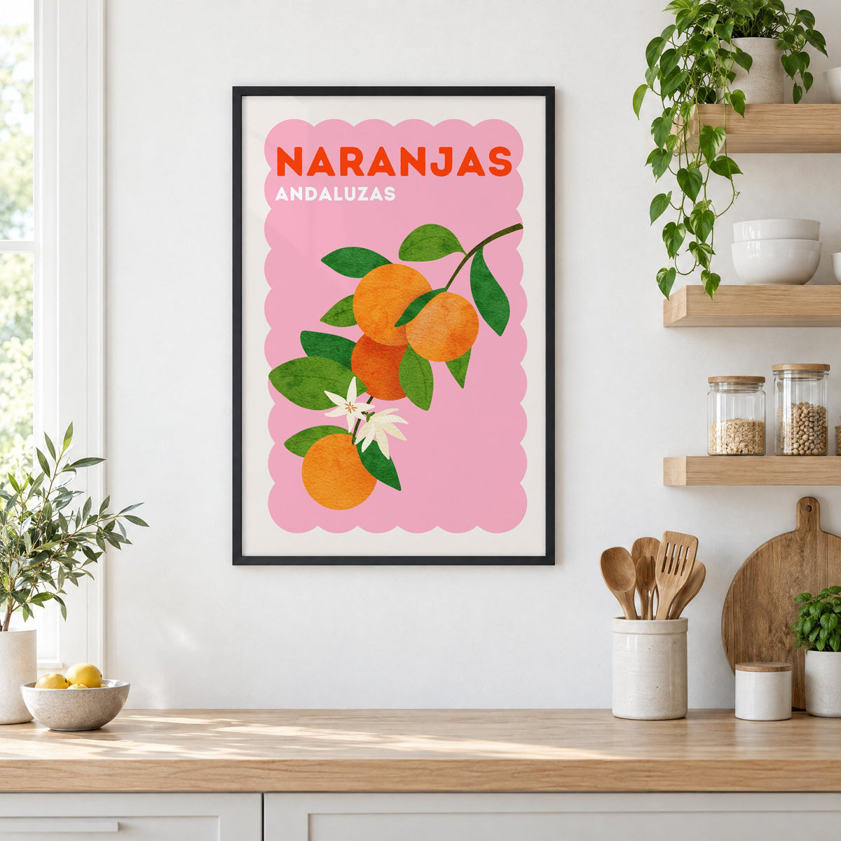 Naranjas Andaluzas orange branch print in a black frame in a white kitchen beside open wood shelves and glass jars