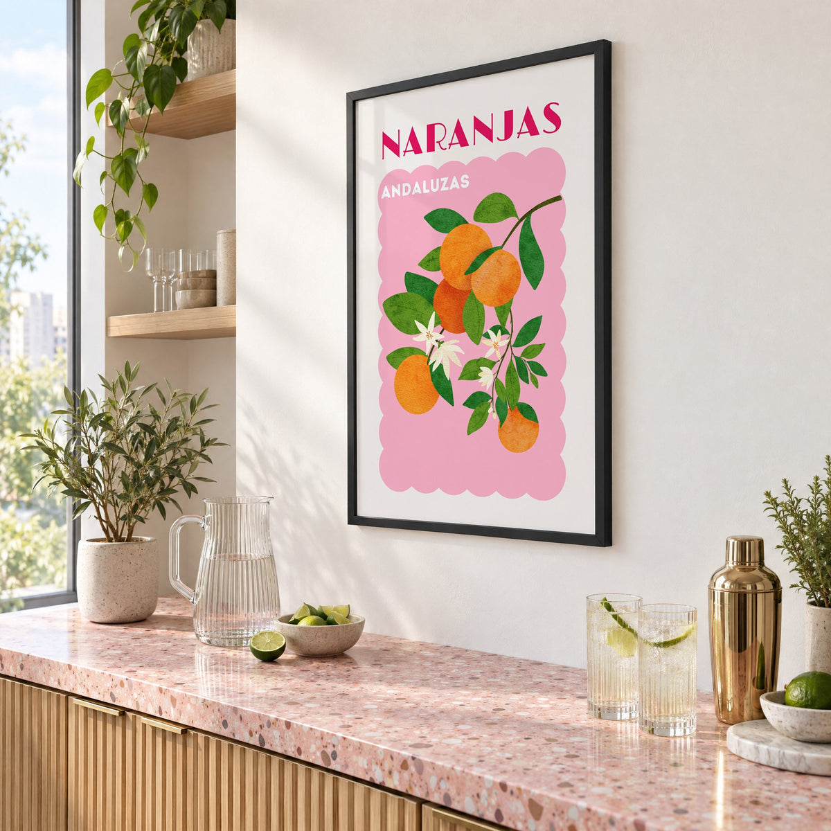 NARANJAS ANDALUZAS orange branch print in a black frame above a pink terrazzo cocktail counter with limes, seen at an angle