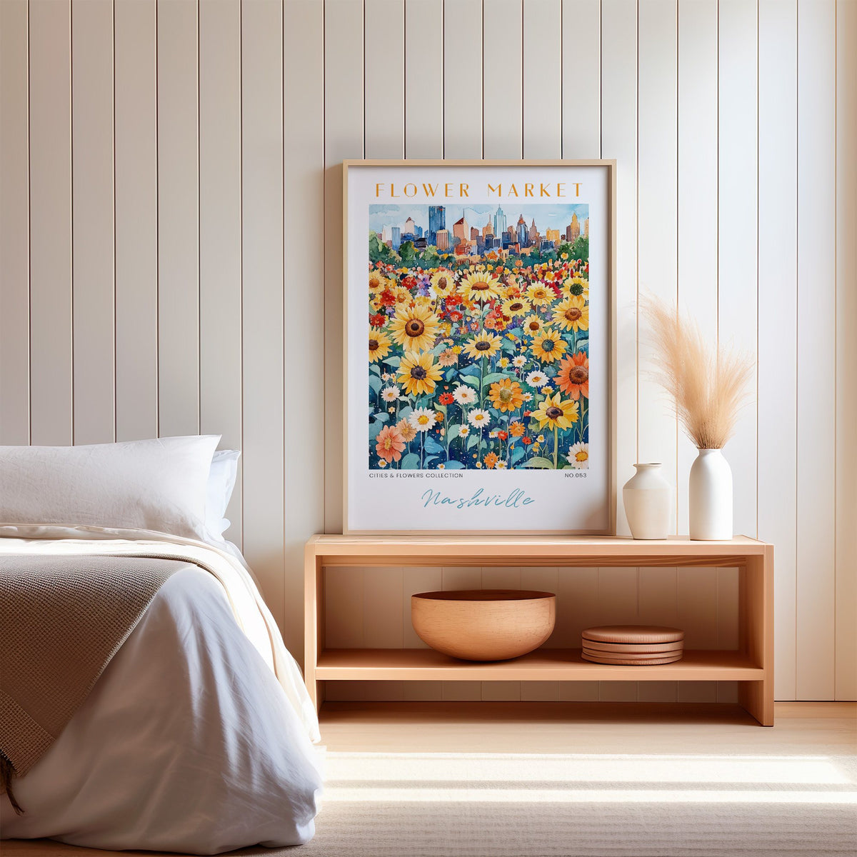 Nashville flower market print in an oak frame on a wood bench against a white shiplap bedroom wall with pampas grass
