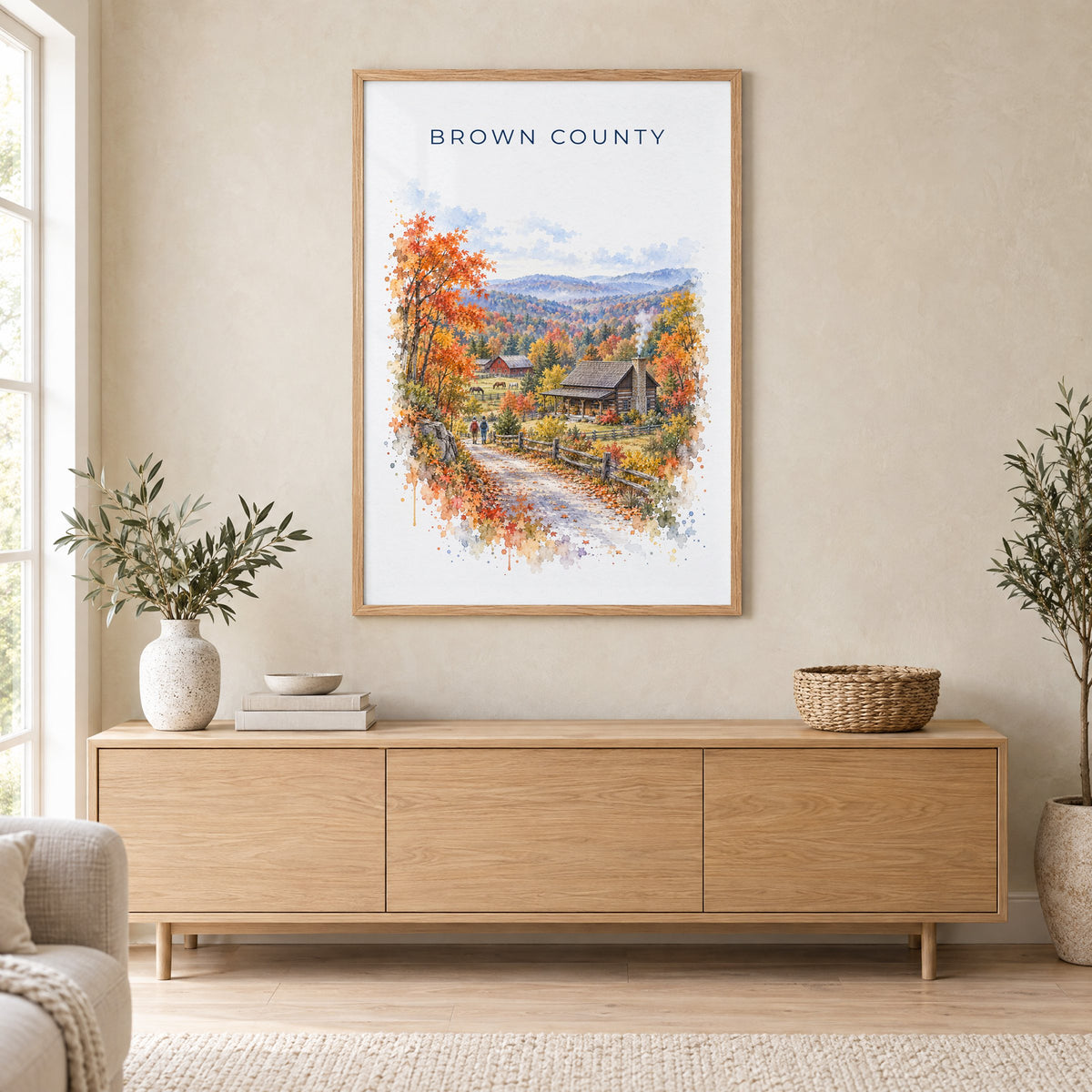Nashville, Indiana watercolor print in an oak frame above a light wood sideboard in a Scandinavian living room