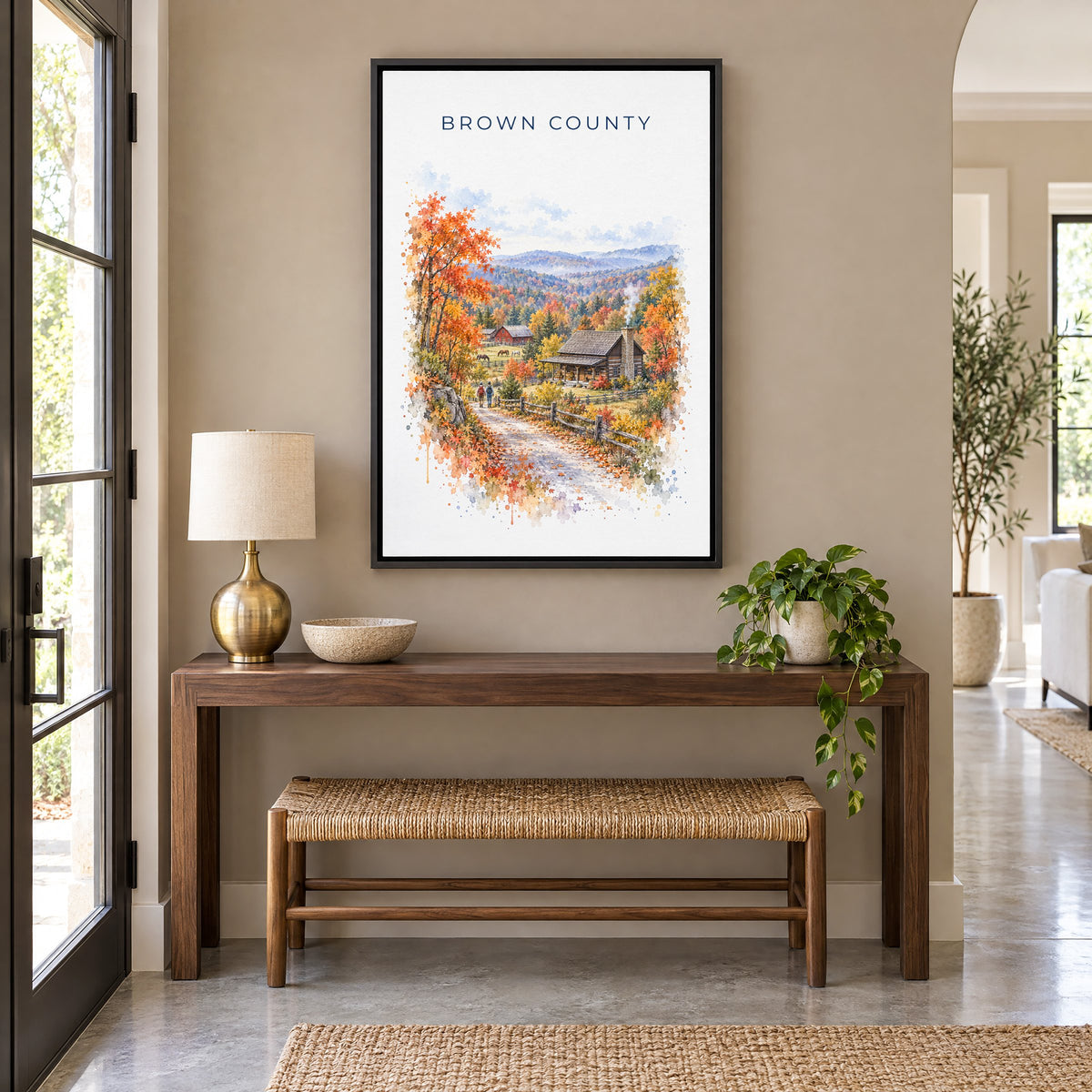 Nashville, Indiana watercolor print as a black floater canvas above a walnut console and woven bench in an entryway