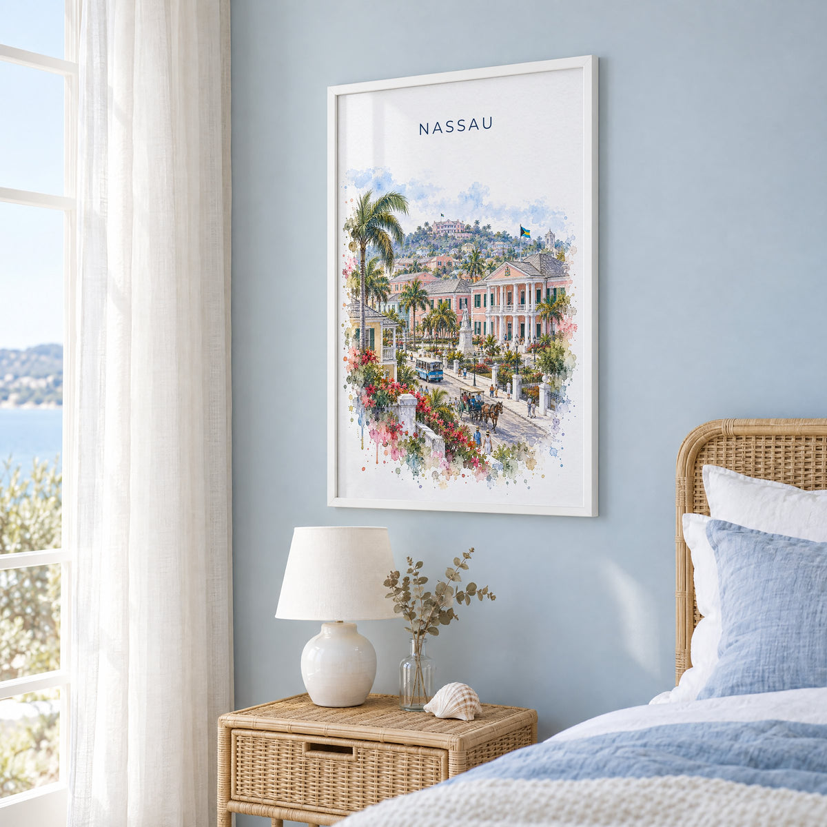 Nassau watercolor print in a white frame on a pale blue wall beside a rattan bed in a coastal bedroom