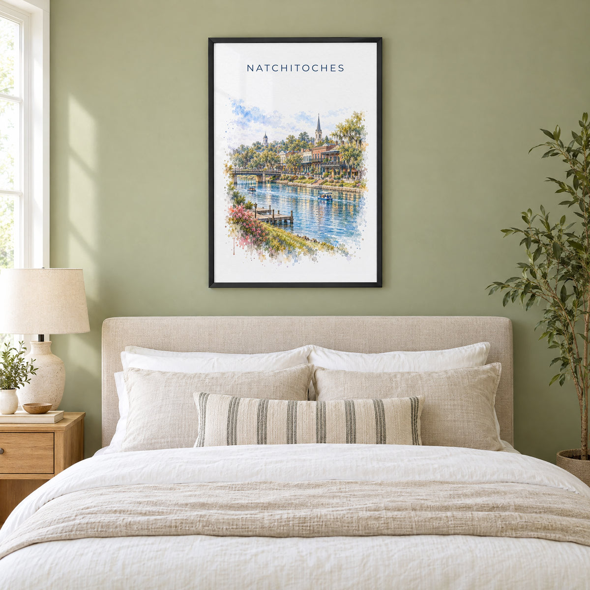 Natchitoches, Louisiana watercolor print in a black frame above an upholstered headboard in a sage green bedroom