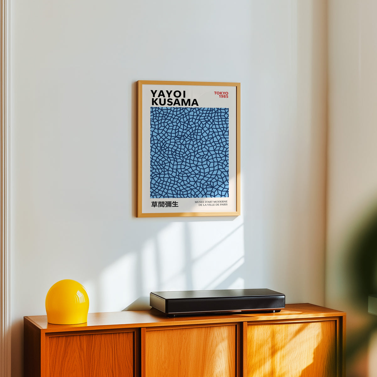 Yayoi Kusama inspired navy net on sky blue print above a sideboard with a yellow lamp