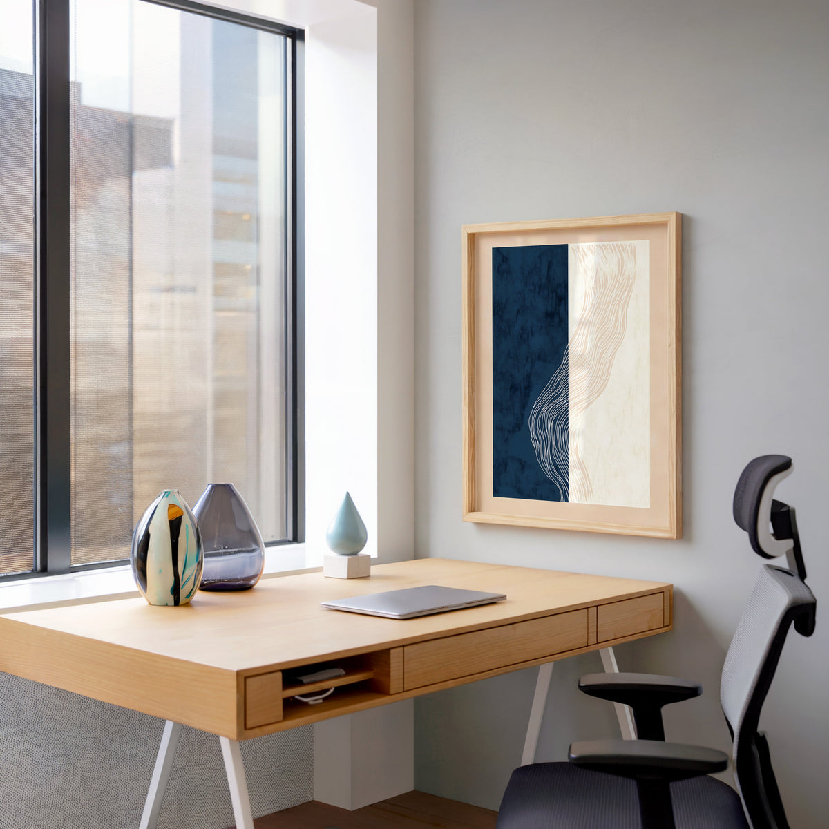 Navy and cream split panel line art print in a pale wood frame above a home office desk by a tall window