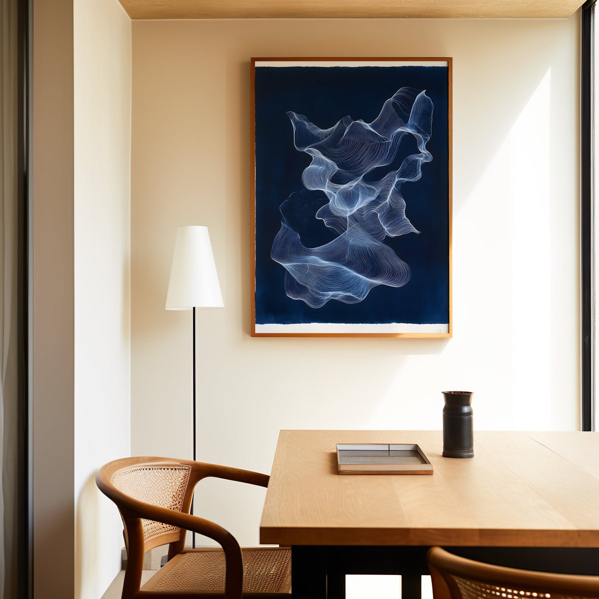 Navy and white line ribbon abstract print in a slim oak frame above a dining table with a cane-back chair