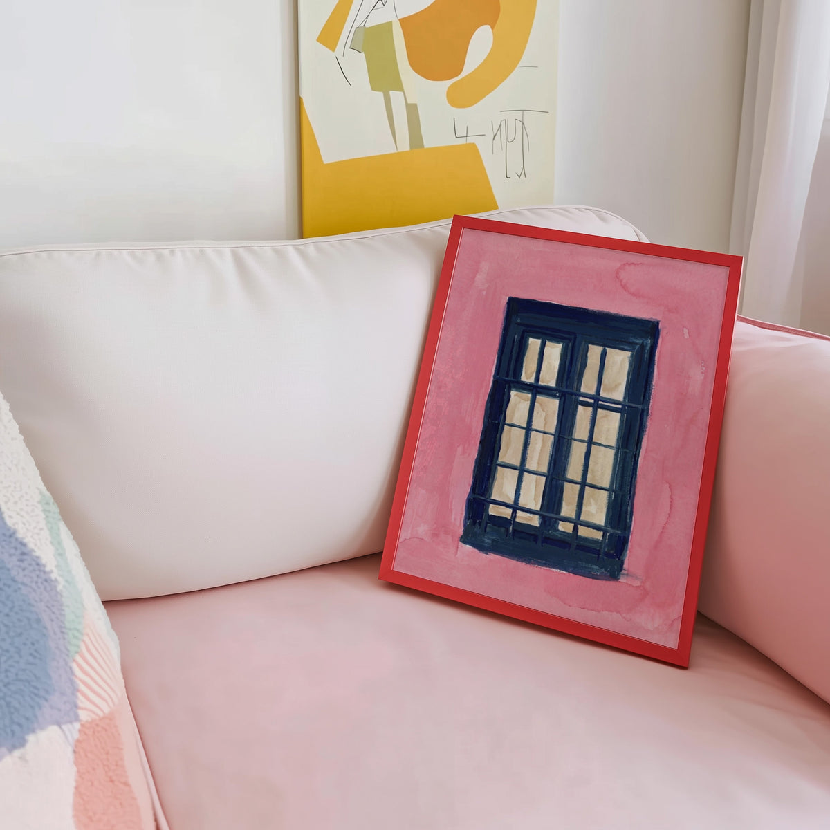 Coral and navy window print shown in a red frame leaning on a blush pink sofa