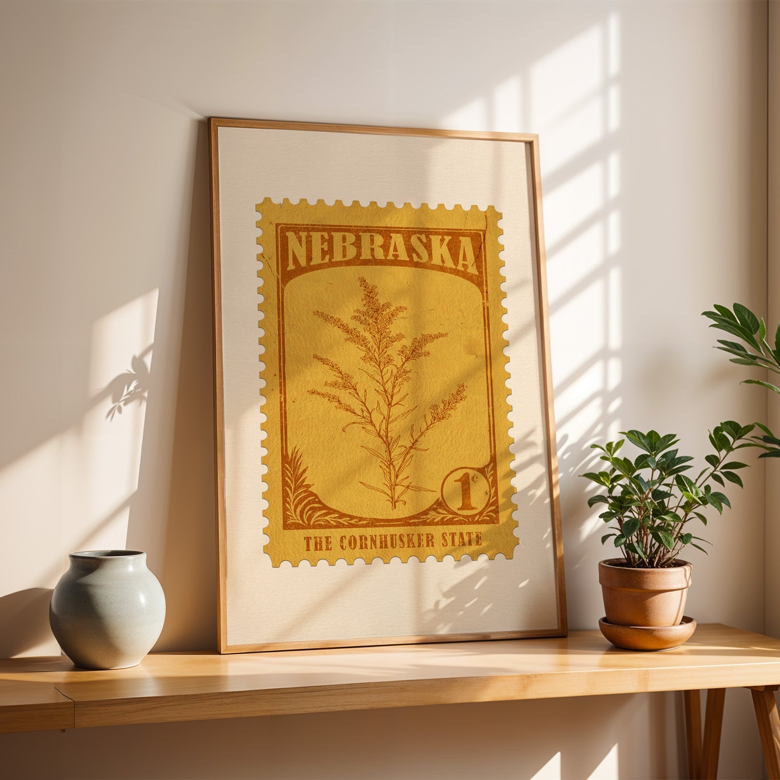 Nebraska goldenrod stamp print in a light oak frame leaning on a wooden table beside a stoneware vase