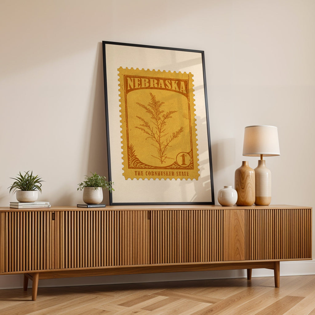 Nebraska state flower print in a black frame leaning on a fluted wood credenza with vases and a lamp