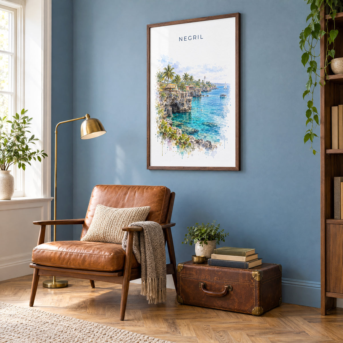 Negril watercolor print in a walnut frame on a blue wall above a leather armchair in a reading nook
