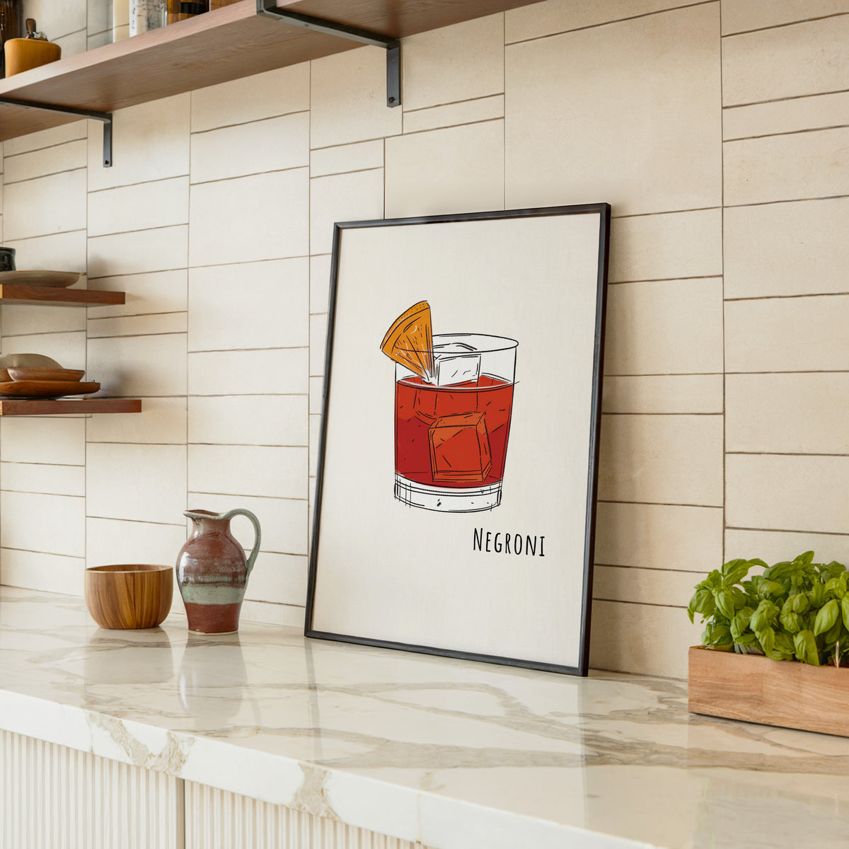 Negroni line print in a black frame leaning on a marble counter in a tiled kitchen