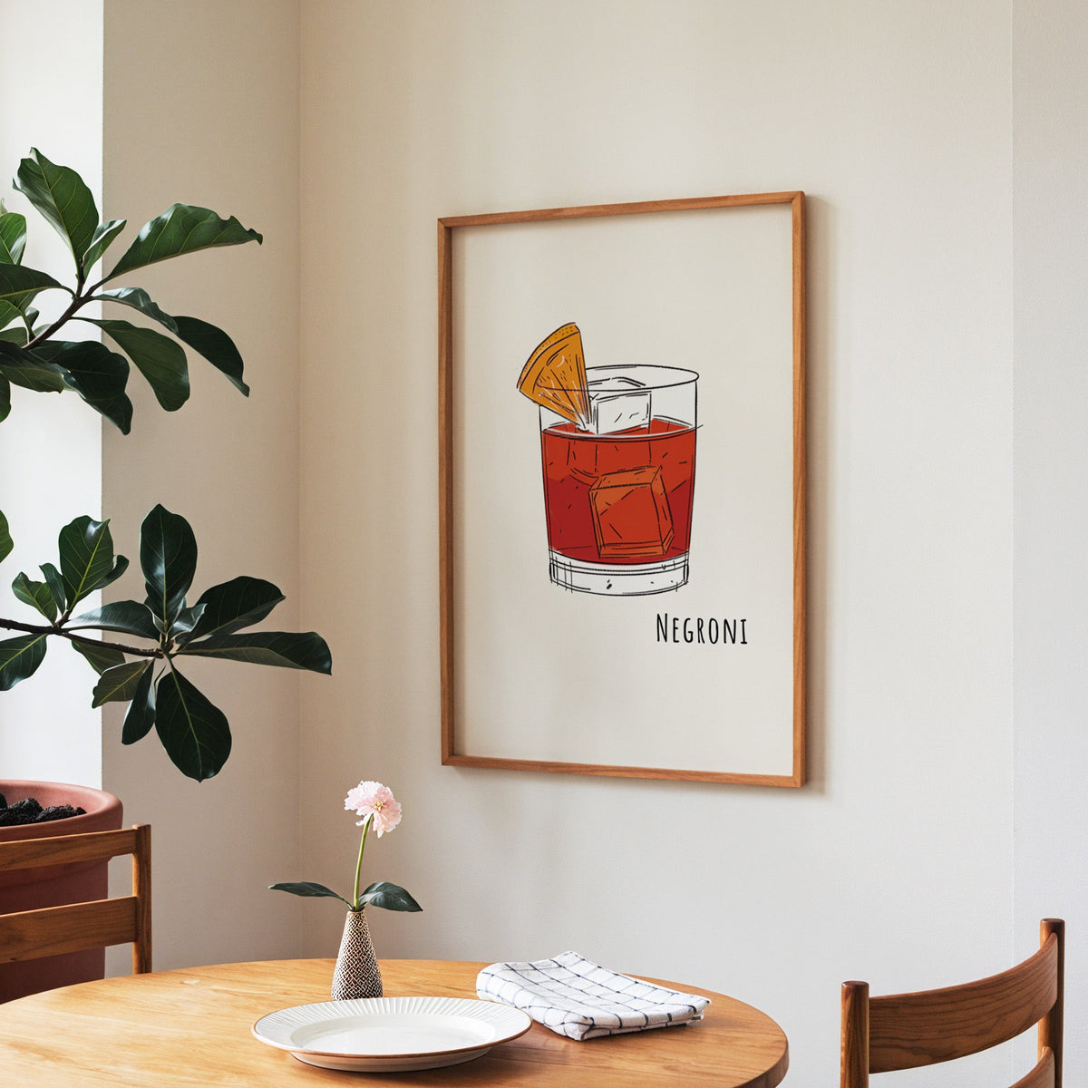 Negroni line print in a walnut frame above a round table beside a fiddle-leaf fig