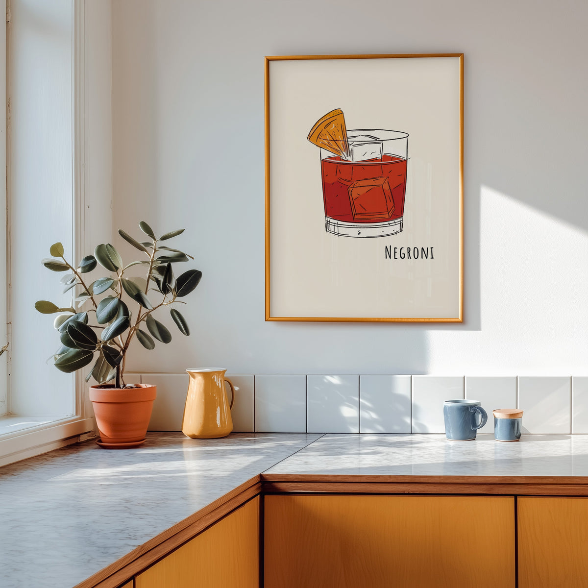 Negroni line print shown in a gold frame above a marble counter in a tan kitchen