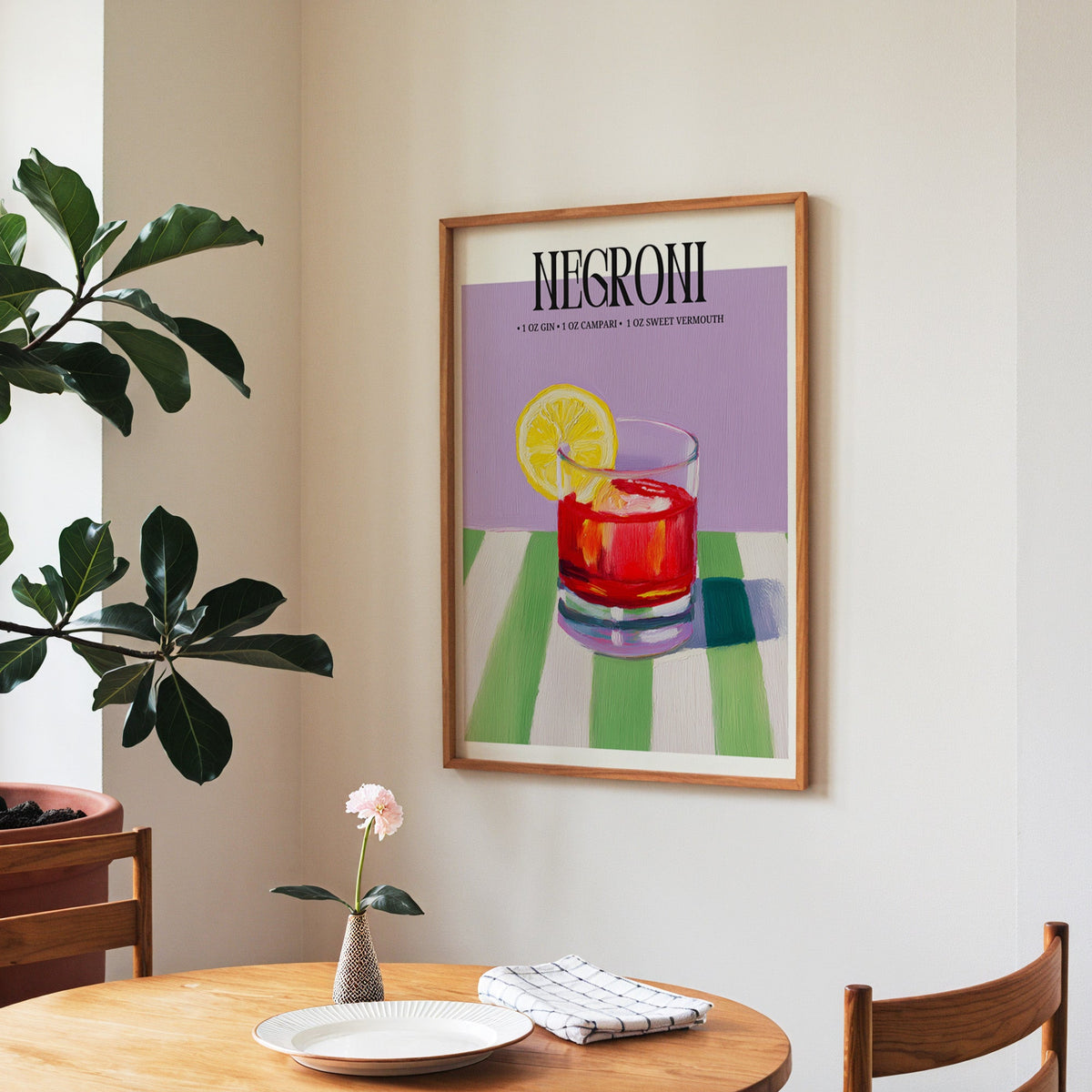 Negroni painterly print in a walnut frame above a round table beside a fiddle-leaf fig