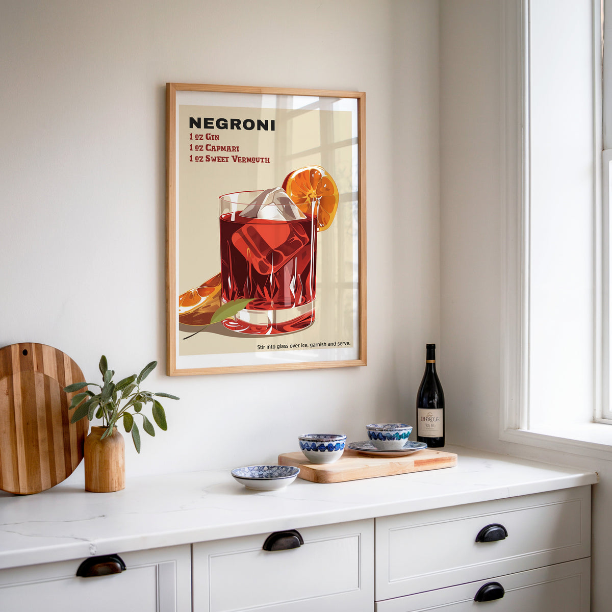 Negroni recipe print in an oak frame above a white sideboard with a bottle of wine