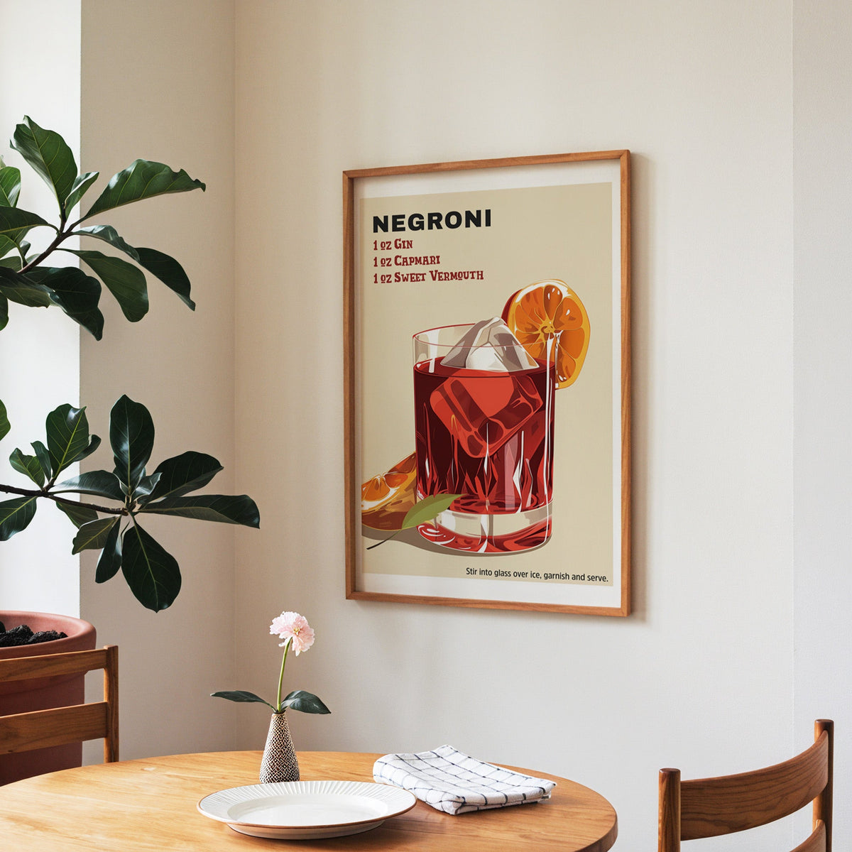 Negroni recipe print in a walnut frame above a round table beside a fiddle-leaf fig