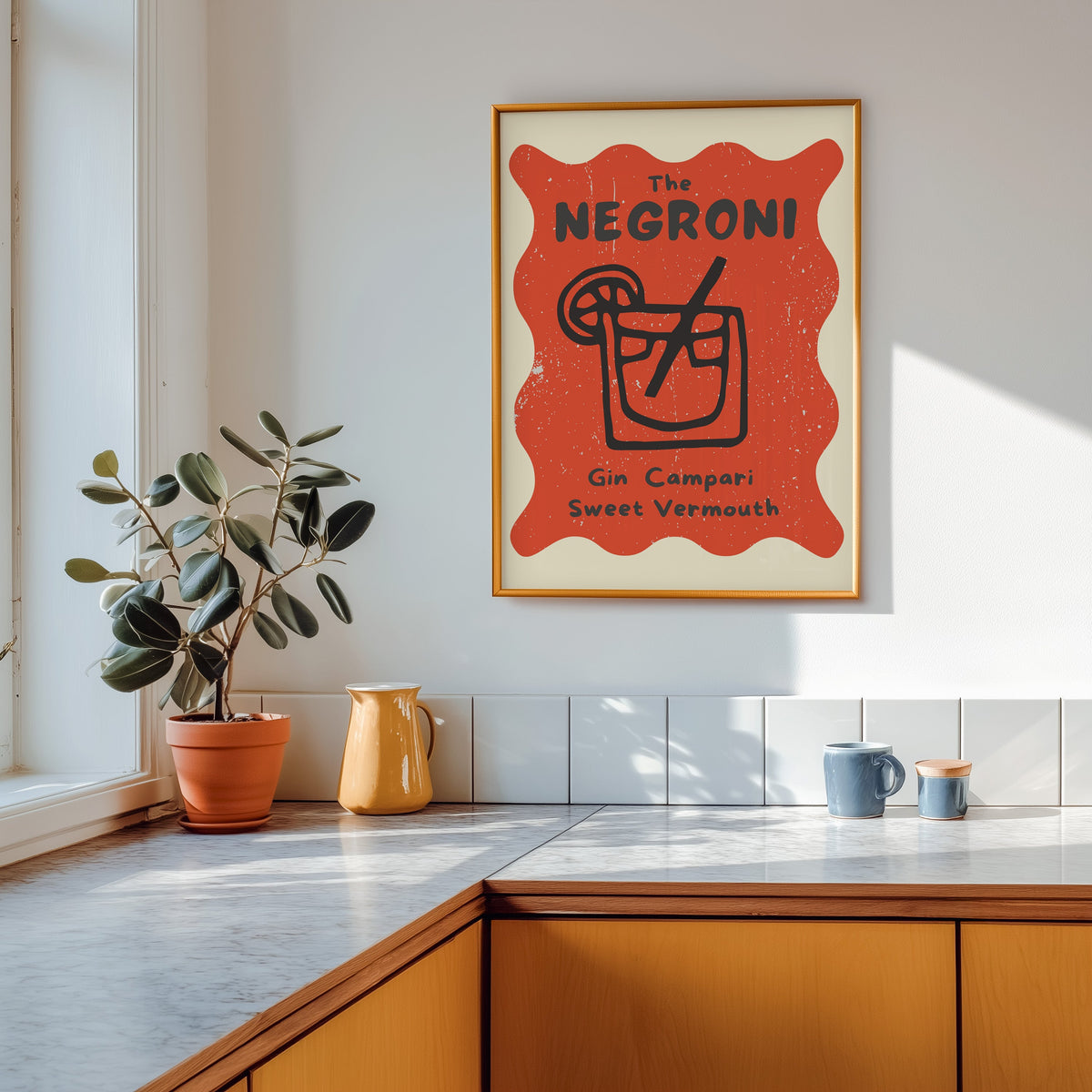 Negroni print shown in a gold frame above a marble counter in a tan kitchen