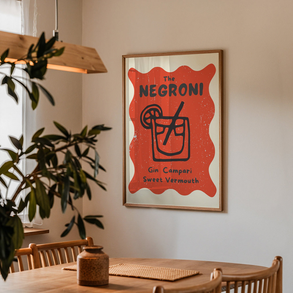 Negroni print in a walnut frame above a dining table with olive branches