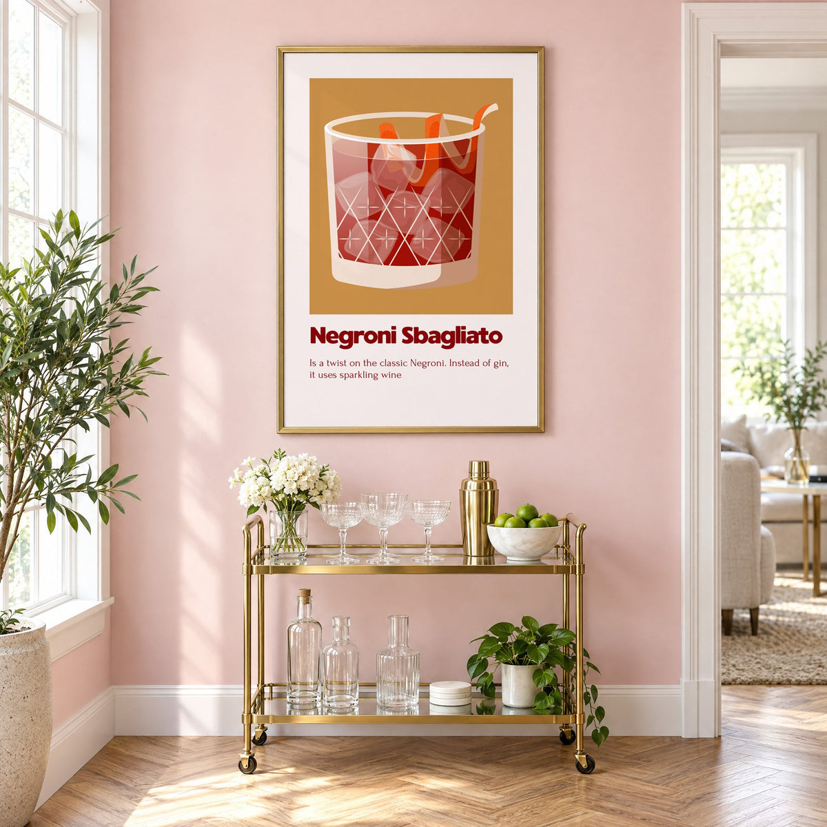 Negroni Sbagliato rocks glass ochre card print in a brass frame on a blush pink wall above a gold bar cart with glassware
