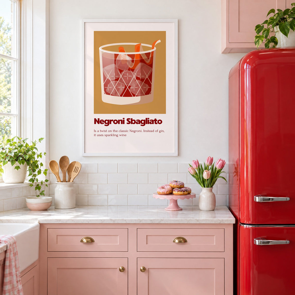Negroni Sbagliato rocks glass ochre card print in a white frame above pink cabinets beside a red retro fridge
